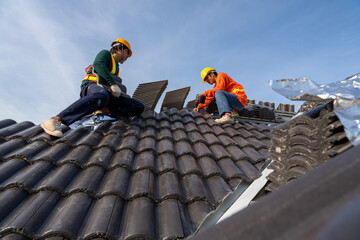 2 Construction worker install new roof, Electric drill used on new roofs with Concrete Roof Tiles,...