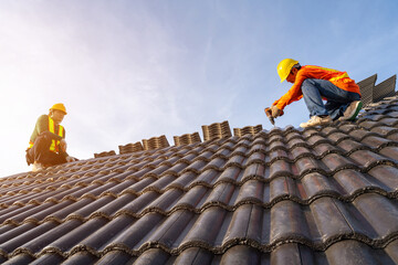 Two Roofer working on roof structure of building on construction site,Roofer using air or pneumatic...