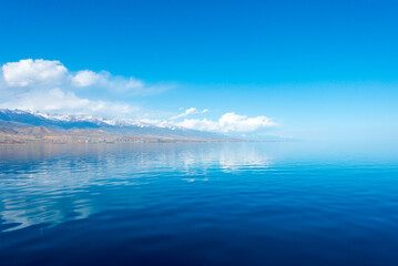 Sverny shore of Lake Issyk-Kul, Kyrgyzstan. View from the ship to the shore. Blue water of a mountain lake.