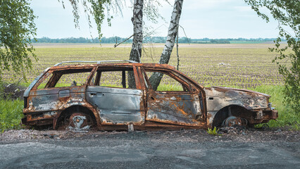 The war in Ukraine, a burned civilian car standing on the side of the road, side view