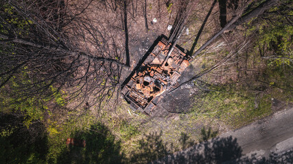 War in Ukraine, destroyed tank, destroyed tank near the road in the woods, vertical view from the drone, aerial photography