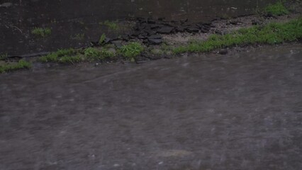 Rain. Fast flow of water. Drops and splashes. Dark asphalt. Weather conditions. Urban environment. Twilight on the street. Wastewater. Close-up. - Powered by Adobe