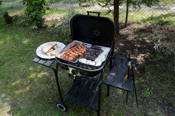 Outdoor barbecues. Sausages, black pudding, onions and baked bread on the grill. Food baked on...