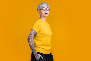senior asian female grey hair fashioned cloth with tattoo arm standing hand gesture with positive...