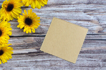 Torn brown paper on wooden surface and sunflower flat lay with copy space.