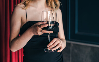 Close-up, a glass of wine in the hands of a woman in an evening dress.