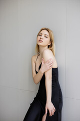 Naklejka premium Young woman in black dress looking at camera at home.
