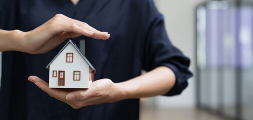 Real estate concept, business woman holding a house icon. House on Hand.Property insurance and...
