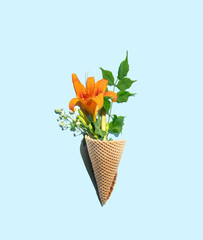 Wrapped ice cream cone and spring inspired floral arrangement. Pastel blue background. 