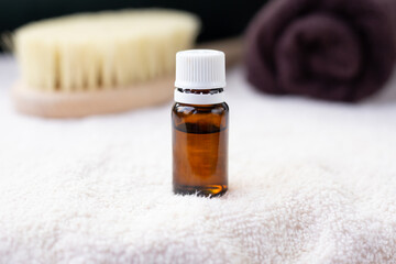 ESSENTIAL OIL in dark bottle , white towel, body brush, copy space, spa procedures products, eco cosmetic