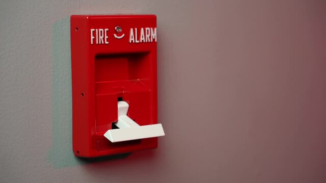 A closeup view pulling down a fire alarm in a commercial building. With police lights in background. Shot at 60fps for optional slow motion use.  	