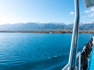 Fototapeta premium Sverny shore of Lake Issyk-Kul, Kyrgyzstan. View from the ship to the shore. Blue water of a mountain lake.