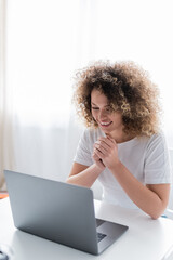 young amazed woman looking at laptop while having video call at home.