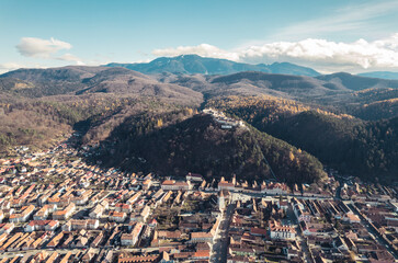Obraz premium Aerial view of Rasnov, Romania shows that the buildings are styled with medieval fortress architecture. Medieval fortification in Brasov. Drone shot of Rasnov Medieval city