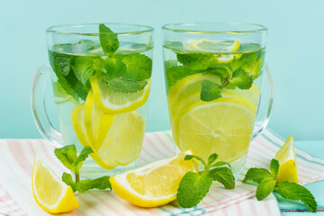 Lemon drink with mint in two glass glasses on a blue background. Detox, fruit water, lemonade, maintaining immunity, proper nutrition.