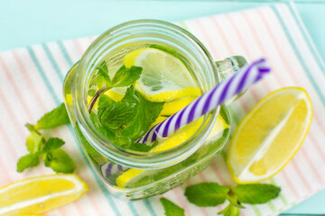 Lemon drink with mint in a glass jar with a straw on a blue background. Top view. Detox, fruit water, lemonade, maintaining immunity, proper nutrition.