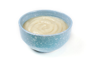 Oatmeal porridge for a baby in a blue mask made of ground cereals on a white isolated background. Side view. Baby's first complementary food, baby nutrition.