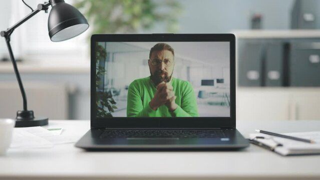 Portable laptop with video conference of bearded caucasian businessman on screen. Bearded man talking and gesturing during online conference meeting.