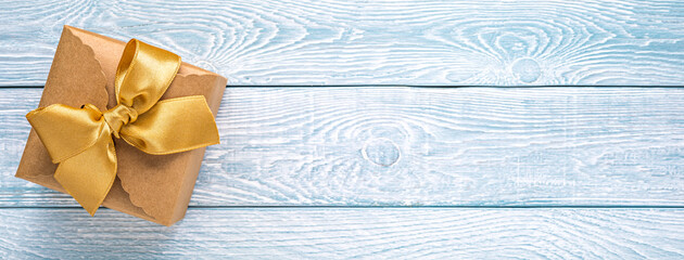 Kraft paper gift box with gold ribbon on blue with white planks