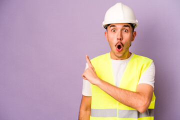 Young hispanic worker man isolated on purple background pointing to the side