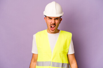 Young hispanic worker man isolated on purple background screaming very angry and aggressive.