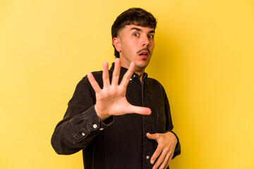 Young caucasian man isolated on yellow background being shocked due to an imminent danger