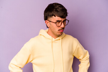 Young caucasian man isolated on purple background frowning face in displeasure, keeps arms folded.