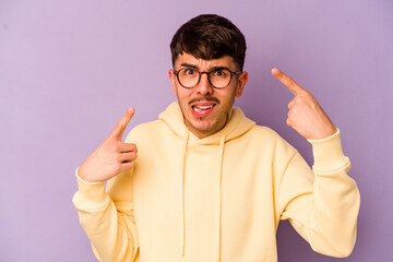 Young caucasian man isolated on purple background showing a disappointment gesture with forefinger.