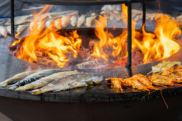 Fototapeta premium Fish, seafood prepared on barbecue grill outdoors close-up, fire flame