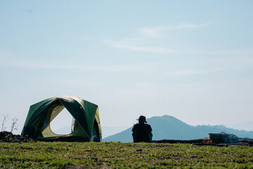 hiker man relax with wellbeing and happy feeling on top of mountain with camping tent