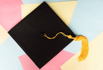 Black graduation cap or hat with yellow tassel on colorful pastel background education Academic cap...