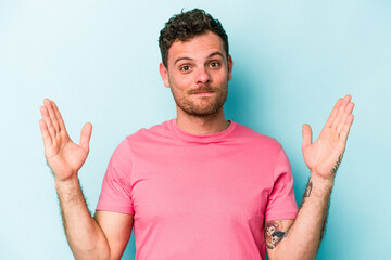 Fototapeta premium Young caucasian man isolated on blue background holding something little with forefingers, smiling and confident.