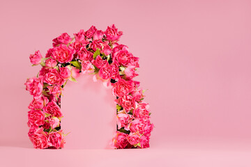 Summer fresh pink roses as decorative framing of arch for presentation cosmetic products or goods, mockup on pink background, copy space. Template for advertising, design, card, poster, flyer.