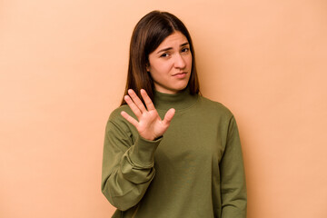 Young hispanic woman isolated on beige background rejecting someone showing a gesture of disgust.