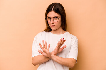 Young hispanic woman isolated on beige background doing a denial gesture