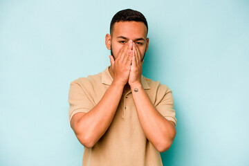 Young hispanic man isolated on blue background shocked, covering mouth with hands, anxious to discover something new.