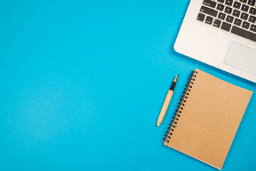 top view of laptop notepad and pen on blue