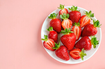 Fresh strawberries flat lay on a white plate close-up on a pink background . Fresh berries, summer harvest, fruits, healthy food, diet concept. copy space for text