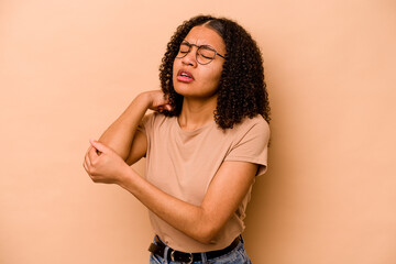 Young African American woman isolated on beige background massaging elbow, suffering after a bad movement.