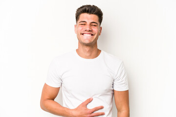 Young caucasian man isolated on white background touches tummy, smiles gently, eating and satisfaction concept.