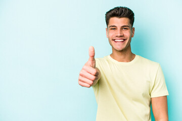 Young caucasian man isolated on blue background smiling and raising thumb up