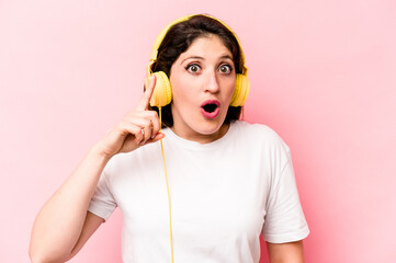 Young caucasian woman listening to music isolated on pink background having an idea, inspiration concept.