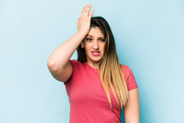 Young caucasian woman isolated on blue background forgetting something, slapping forehead with palm and closing eyes.