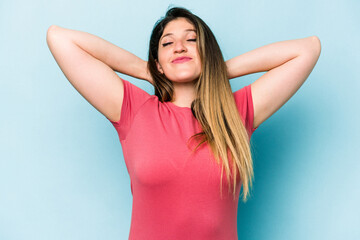 Young caucasian woman isolated on blue background feeling confident, with hands behind the head.