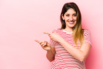 Young caucasian woman isolated on pink background excited pointing with forefingers away.