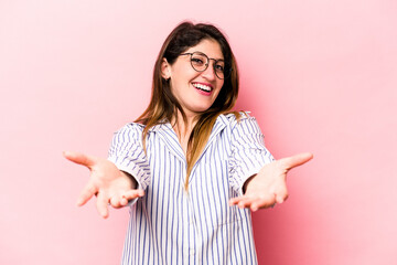 Young caucasian woman isolated on pink background showing a welcome expression.