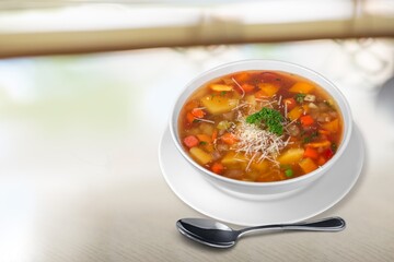 Tasty clear soup with beef slices and vegetables. Served in bowl on desk