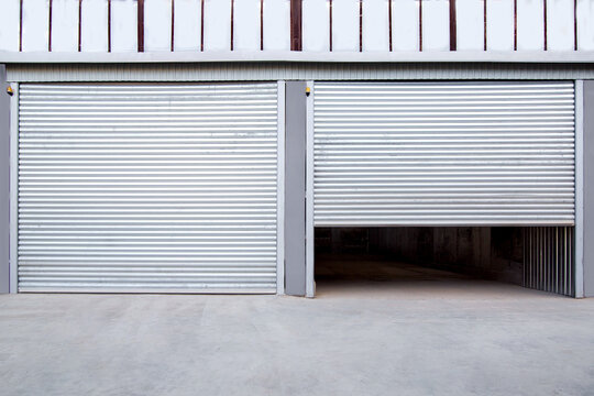 2 Gray Iron Shutter Door? Of Garage And Industrial Building Warehouse Exterior Facade With Grey Concrete Road, Front View On Closing Gate Nobody.