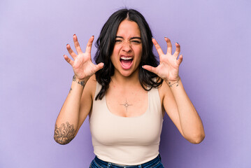 Young hispanic woman isolated on purple background showing claws imitating a cat, aggressive...