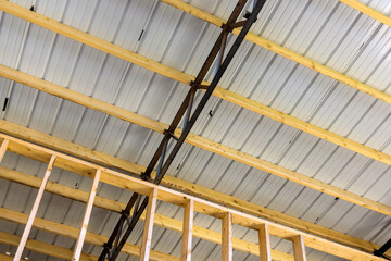 Obraz premium The roof of the new metal frame warehouse is covered with roofing panels in construction site